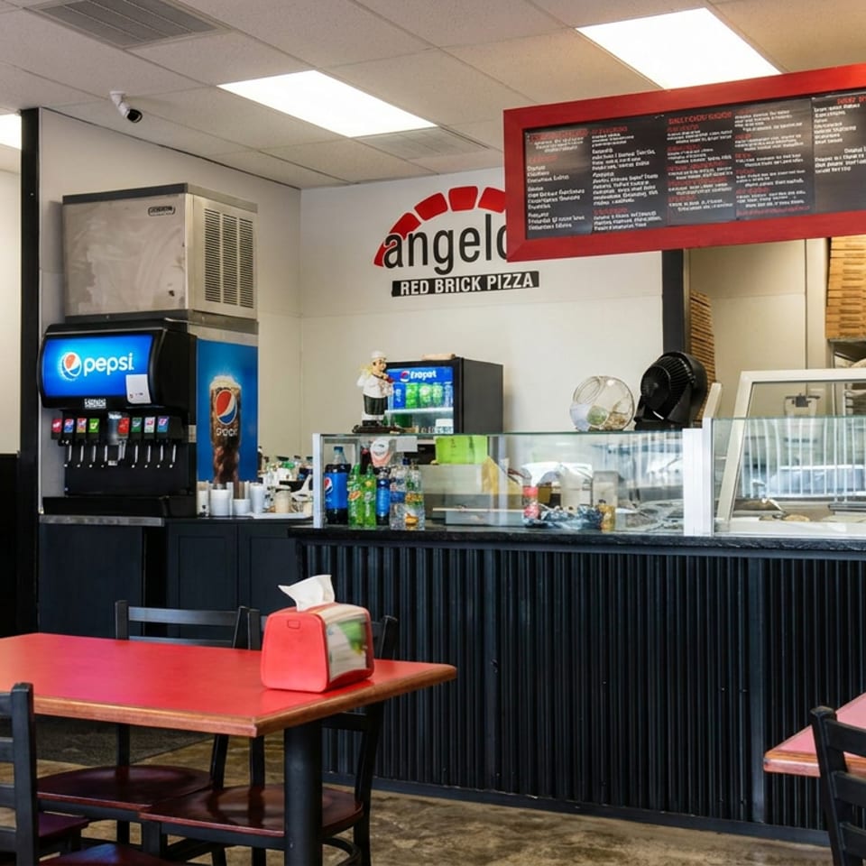 Angelo Red Brick Pizza dining area with red tables, black chairs, soda fountain, display counter, and menu board.
